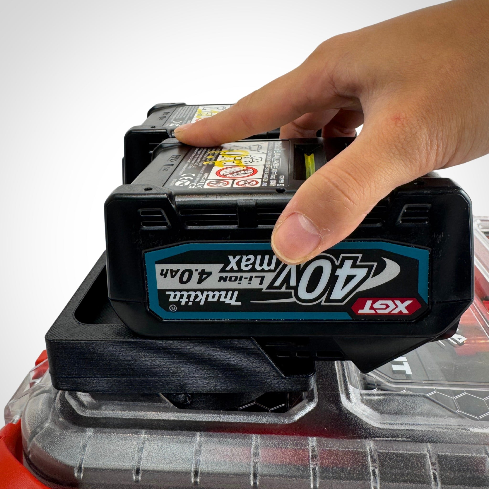 Hand reaching in to pick up a Makita 40V battery from the adaptor insert, highlighting smooth access within the PACKOUT™.