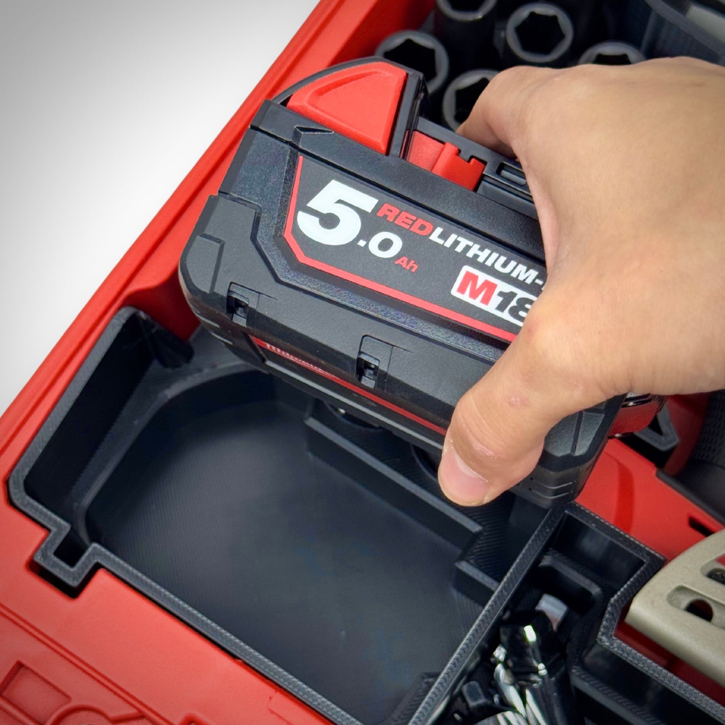 Hand lifting the battery from the insert, clearly showing socket arrangement and easy tool access within the PACKOUT™ Compact Organiser.
