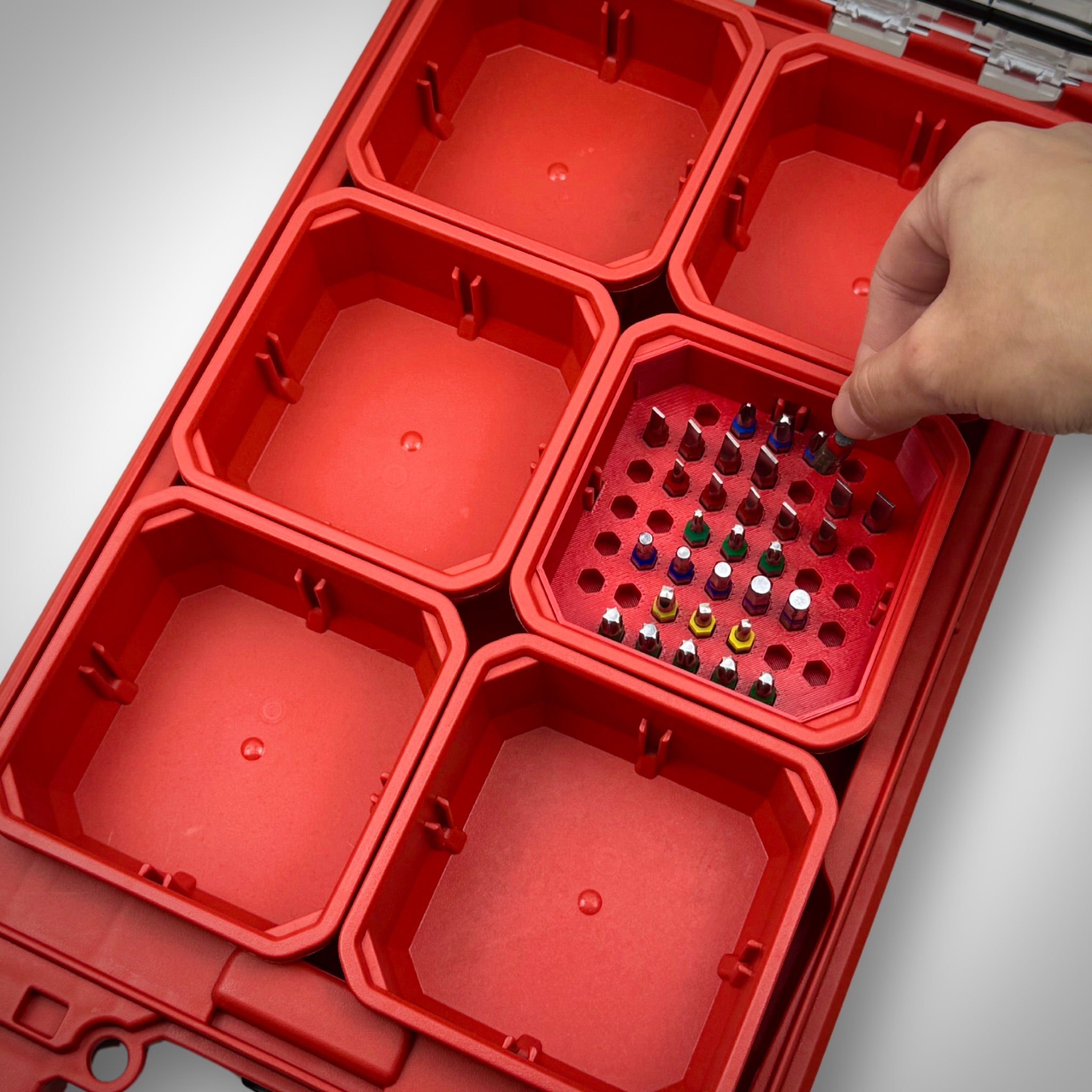 Hand picking up an impact bit from the red Low-Profile Bit Holder Insert inside a Milwaukee PACKOUT™ bin, showing easy and organized access.