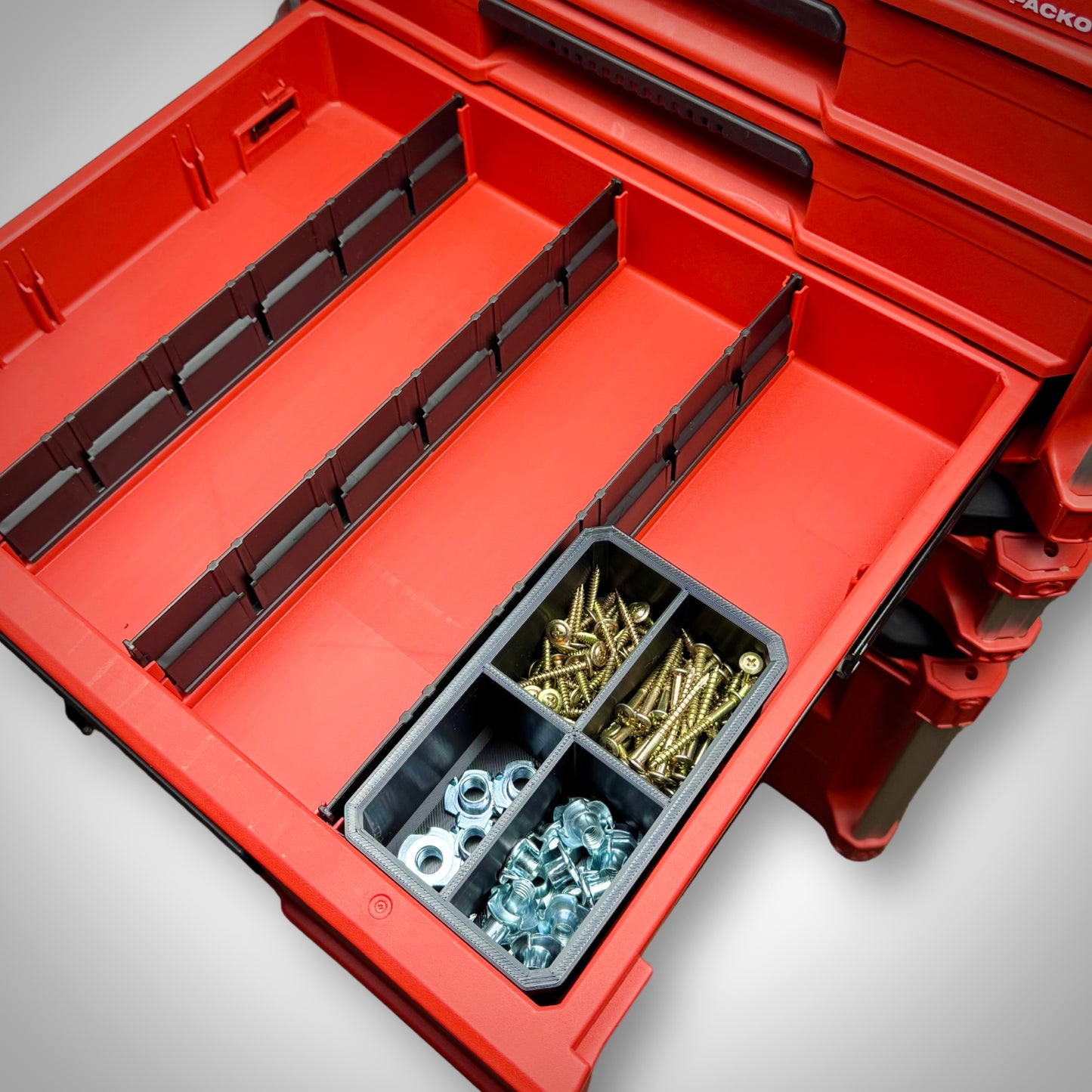 Milwaukee PACKOUT™ 4-Way Divider Bin loaded with small tools and parts, organised inside the 4-Drawer Toolbox.