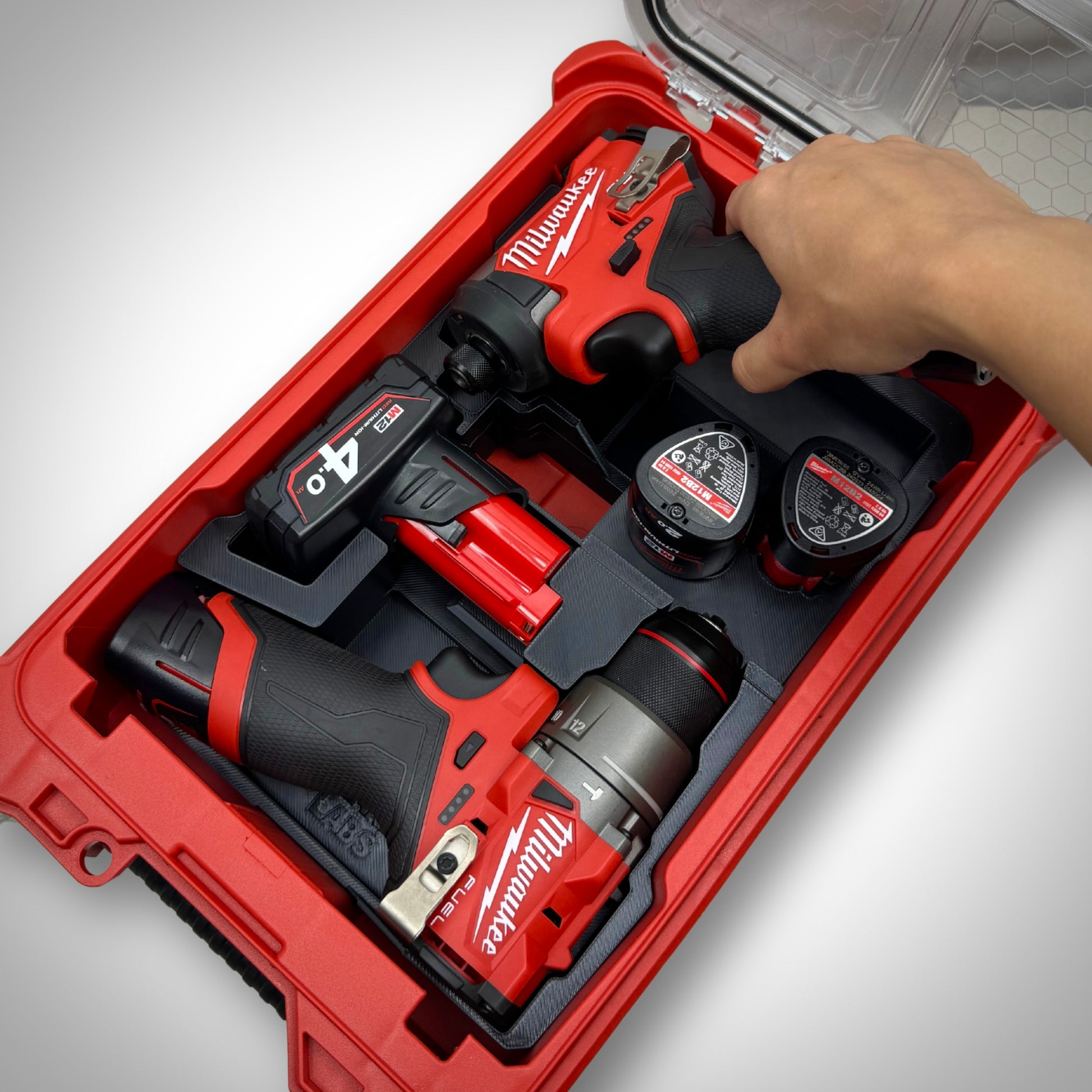Hand lifting the M12 Impact from the insert, with other tools and accessories securely stored in their designated spots.