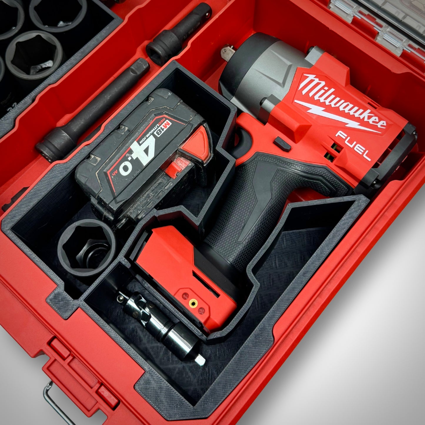 Impact wrench, multiple M18 batteries, and accessories securely arranged in the custom insert within the Milwaukee PACKOUT™ Organiser