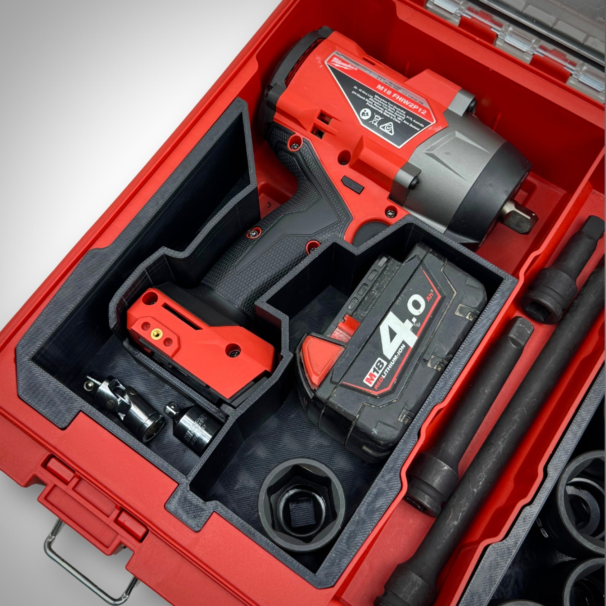Impact wrench, multiple M18 batteries, and accessories securely arranged in the custom insert within the Milwaukee PACKOUT™ Organiser