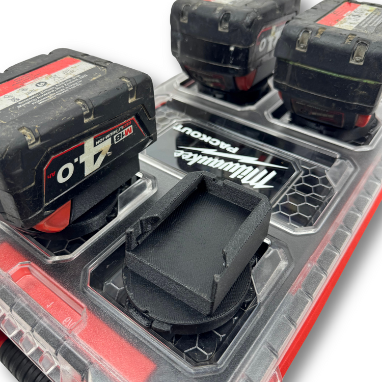 M18 battery adapter insert shown empty atop the Milwaukee PACKOUT™, highlighting the molded compartments.