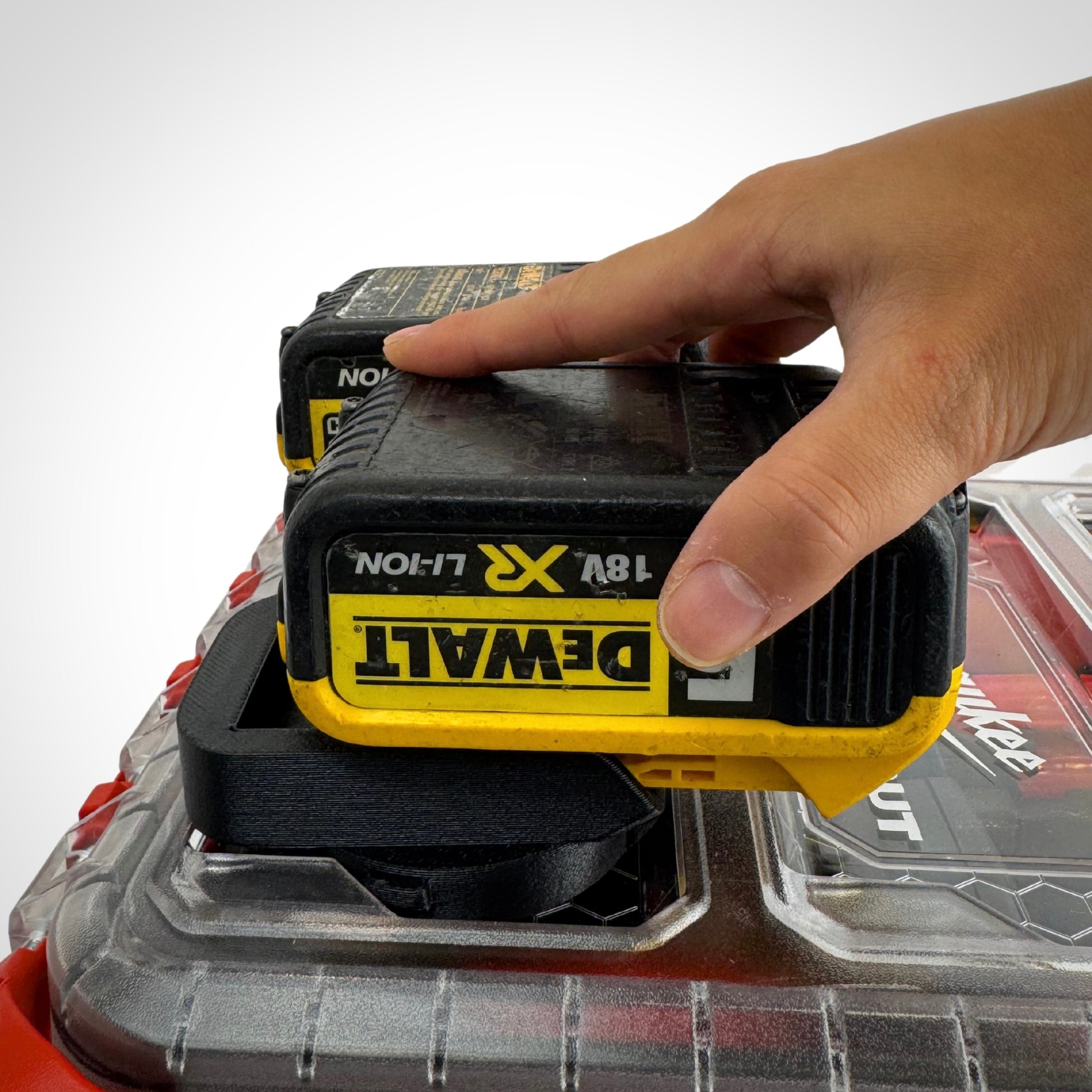 Hand lifting a DeWalt 18V battery from the insert adaptor atop the PACKOUT™, showcasing quick and easy access.