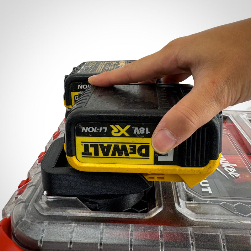 Hand lifting a DeWalt 18V battery from the insert adaptor atop the PACKOUT™, showcasing quick and easy access.