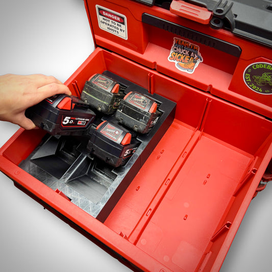 Close-up of a hand lifting an M18 battery from the insert inside the Milwaukee PACKOUT™ Two-Drawer Toolbox, demonstrating easy access and organised layout.