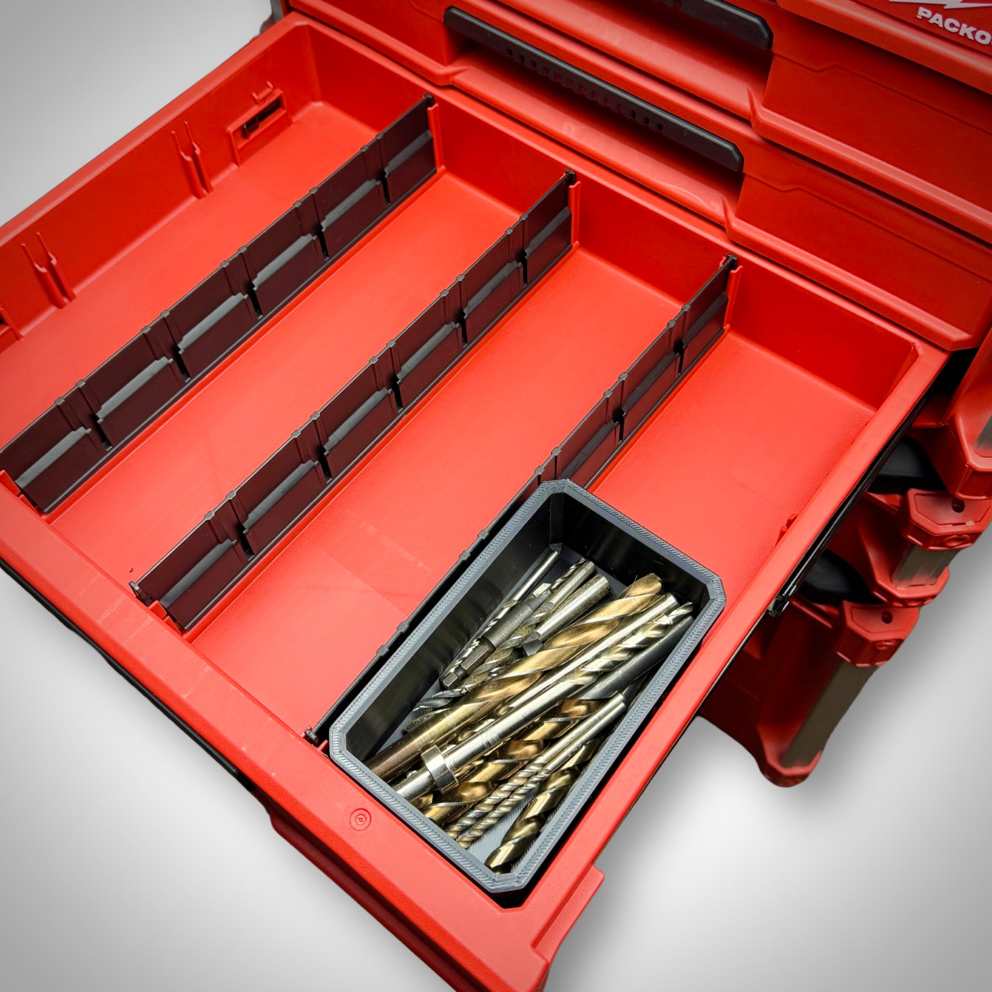 Full-sized Milwaukee PACKOUT™ Full Bin loaded with large items, neatly fitted inside the 4-Drawer Toolbox.
