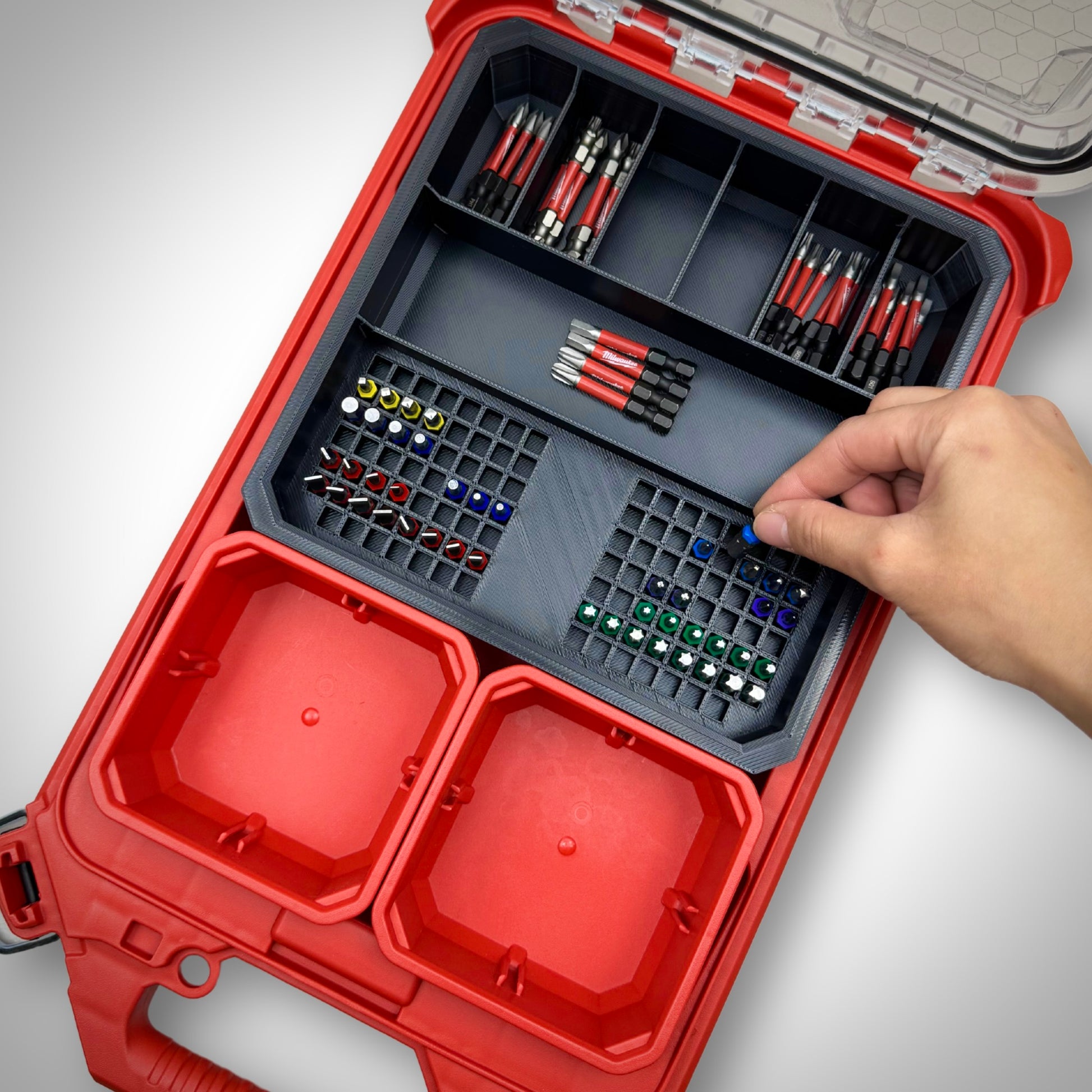 Hand picking a 50mm impact bit from the loaded Impact Bit Holder V2 inside the Milwaukee PACKOUT™ Low Profile Organiser, demonstrating quick and easy access.