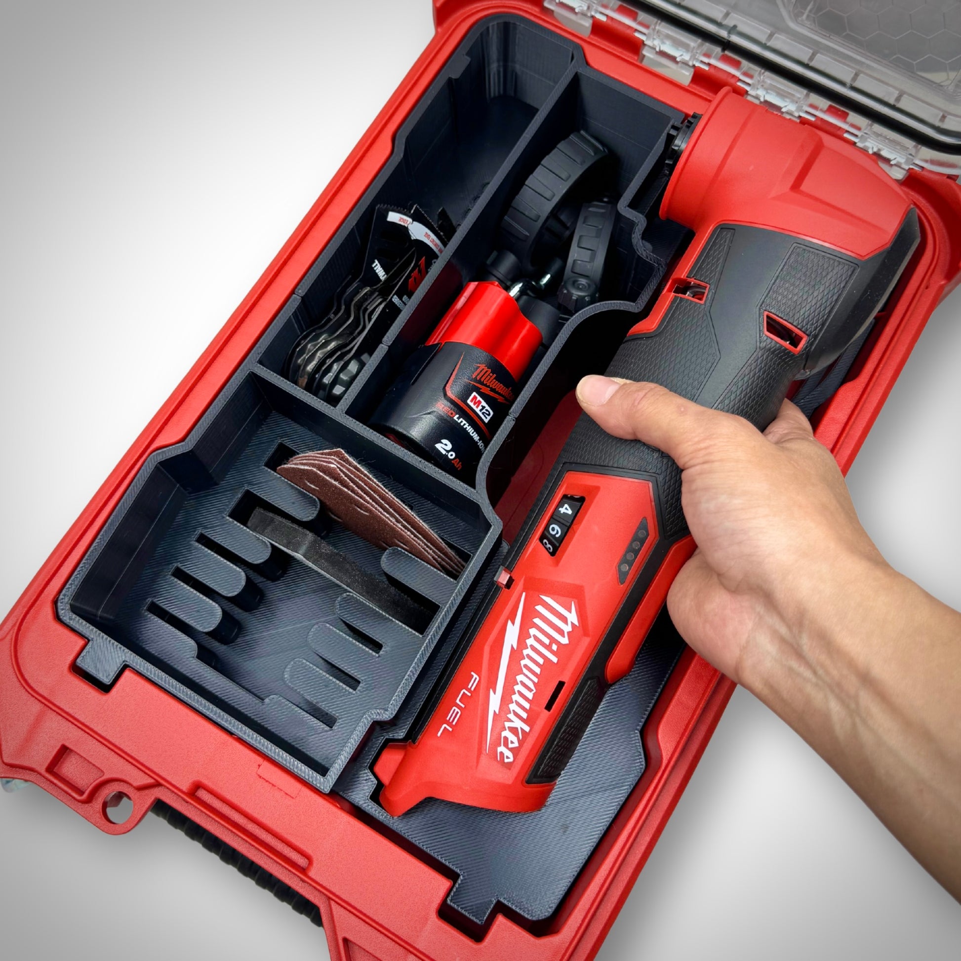 Hand lifting the M12 FUEL Multi-Tool from the insert inside the PACKOUT™ Compact Organiser, demonstrating quick and easy access.