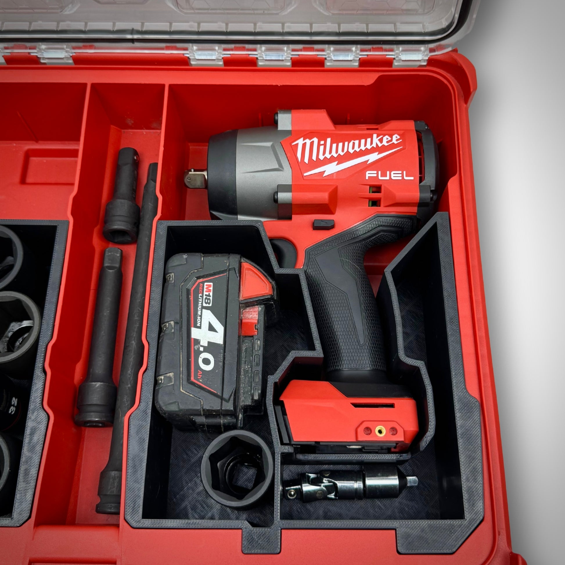 Impact wrench, multiple M18 batteries, and accessories securely arranged in the custom insert within the Milwaukee PACKOUT™