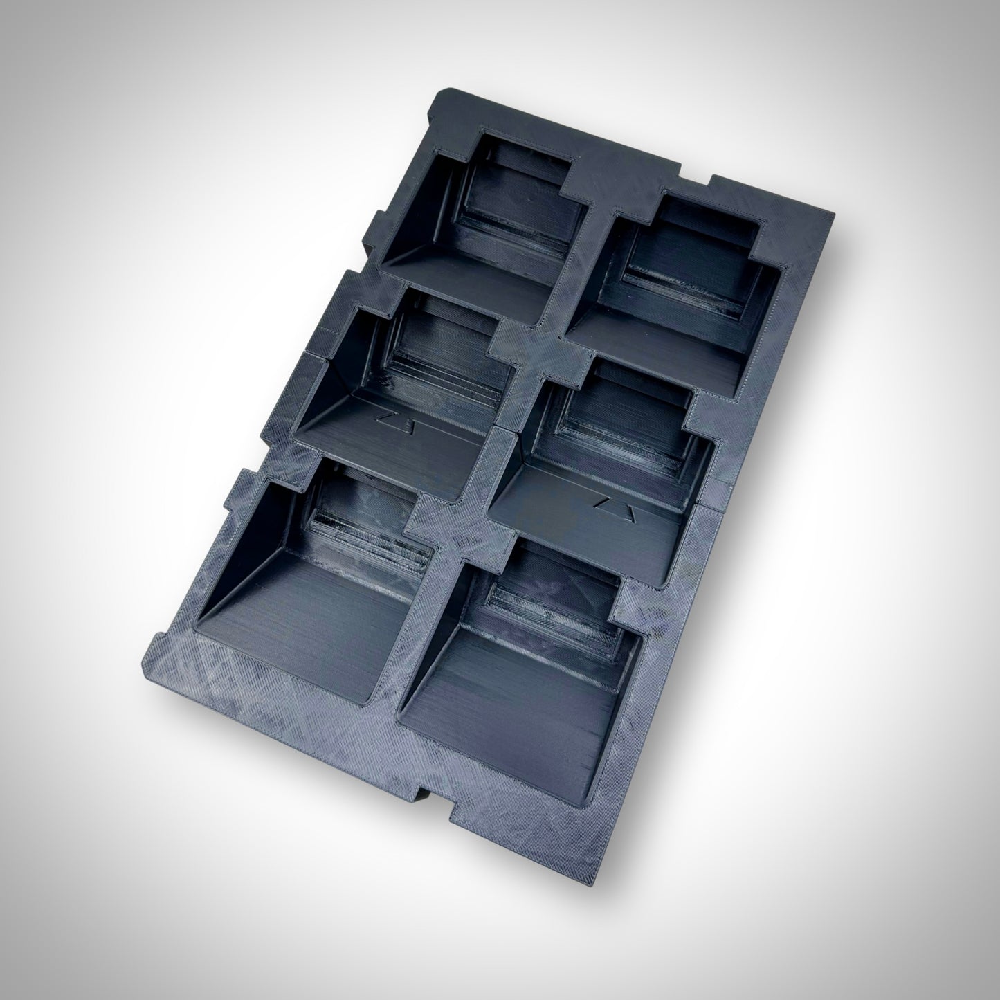 M18 Battery Storage Insert displayed outside of the toolbox on a flat surface, showcasing its structure and six battery slots.