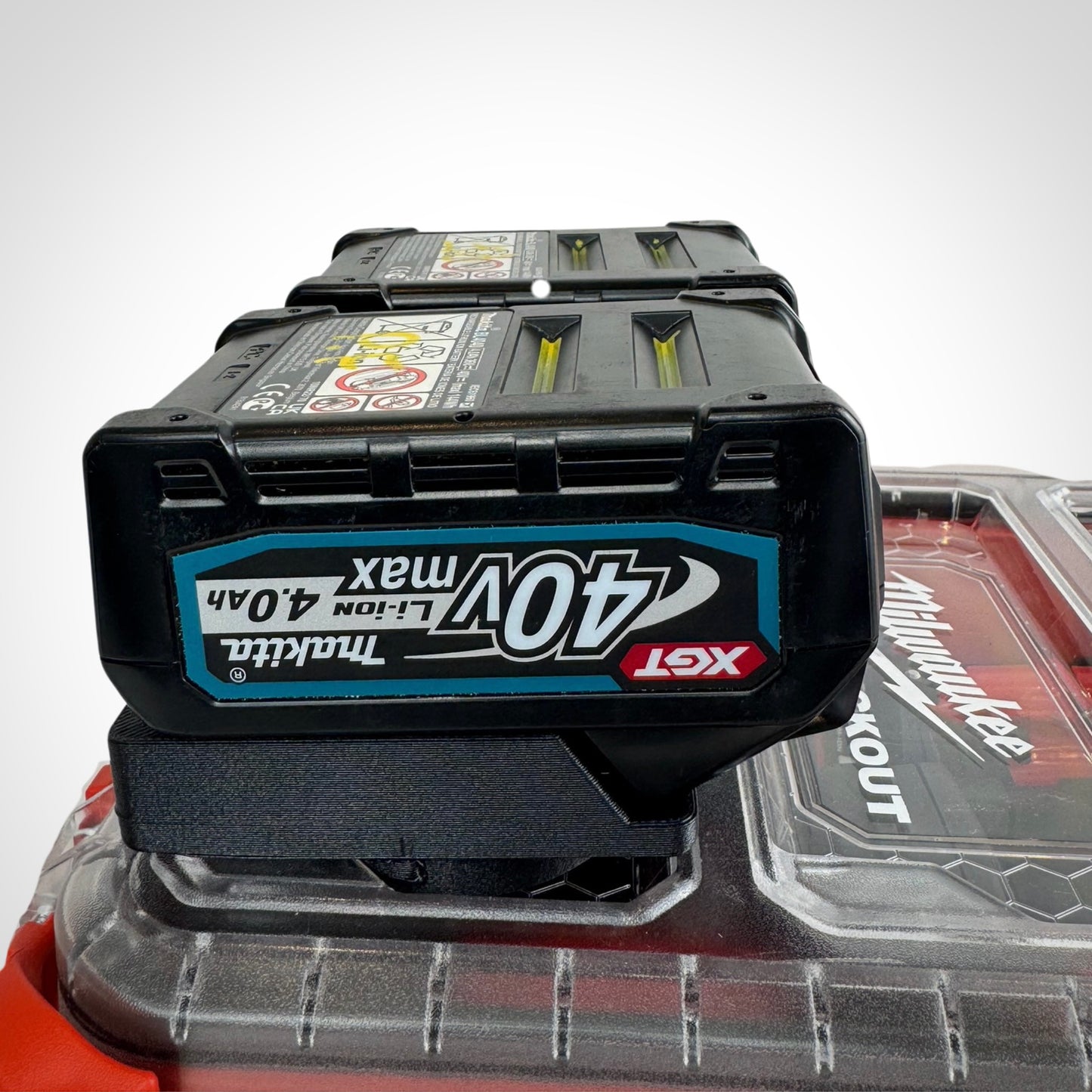 Makita 40V batteries neatly secured in the adaptor insert atop a Milwaukee PACKOUT™ Compact Organiser, showcasing snug compatibility.