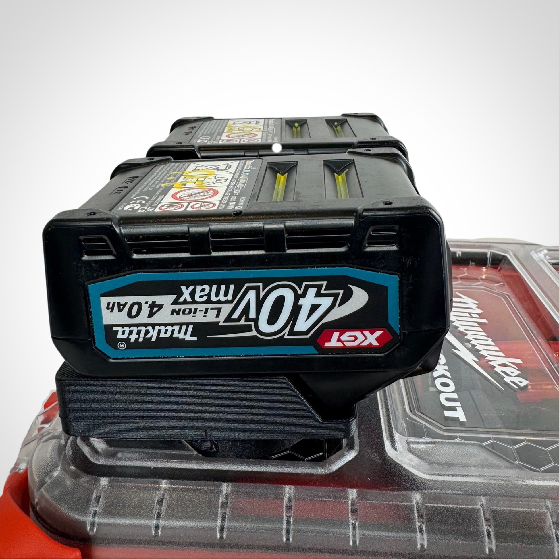 Makita 40V batteries neatly secured in the adaptor insert atop a Milwaukee PACKOUT™ Compact Organiser, showcasing snug compatibility.