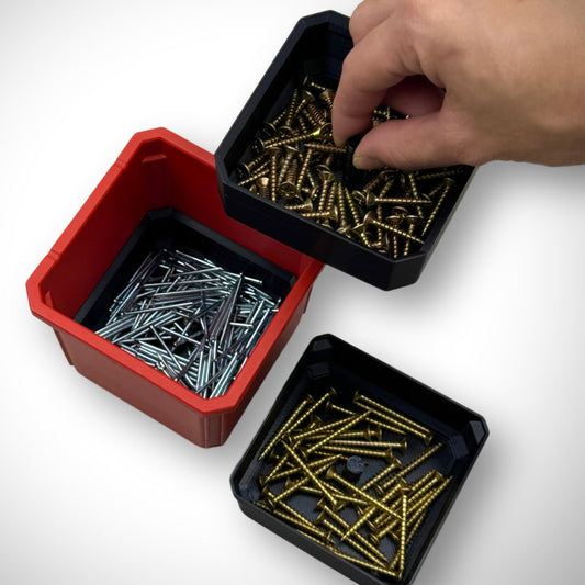 Hand lifting a section of the triple stack bin dividers filled with screws and fittings inside the Milwaukee PACKOUT™ Medium Organiser, showing easy access to organized small parts.