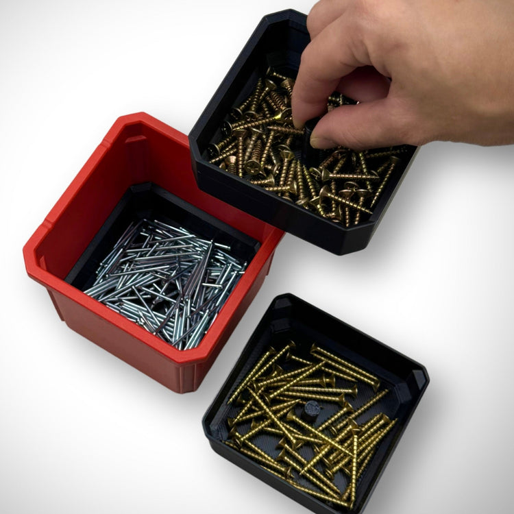 Hand lifting a section of the triple stack bin dividers filled with screws and fittings inside the Milwaukee PACKOUT™ Medium Organiser, showing easy access to organized small parts.