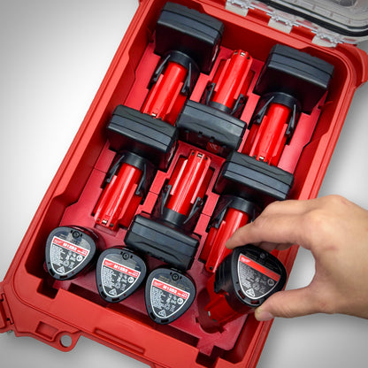 Hand picking an M12 battery from the fully loaded red M12 Battery Storage Insert inside the Milwaukee PACKOUT™ Compact Organiser, showing easy and quick battery access.