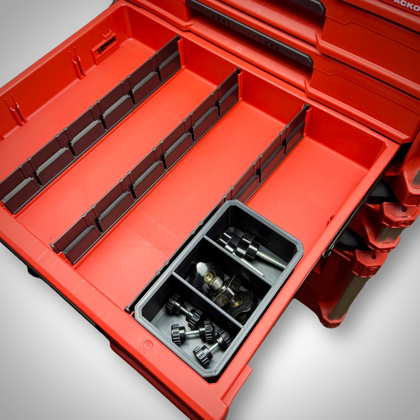 Milwaukee PACKOUT™ 3-Way Divider Bin fully loaded with fittings and hardware, securely placed inside the 4-Drawer Toolbox.