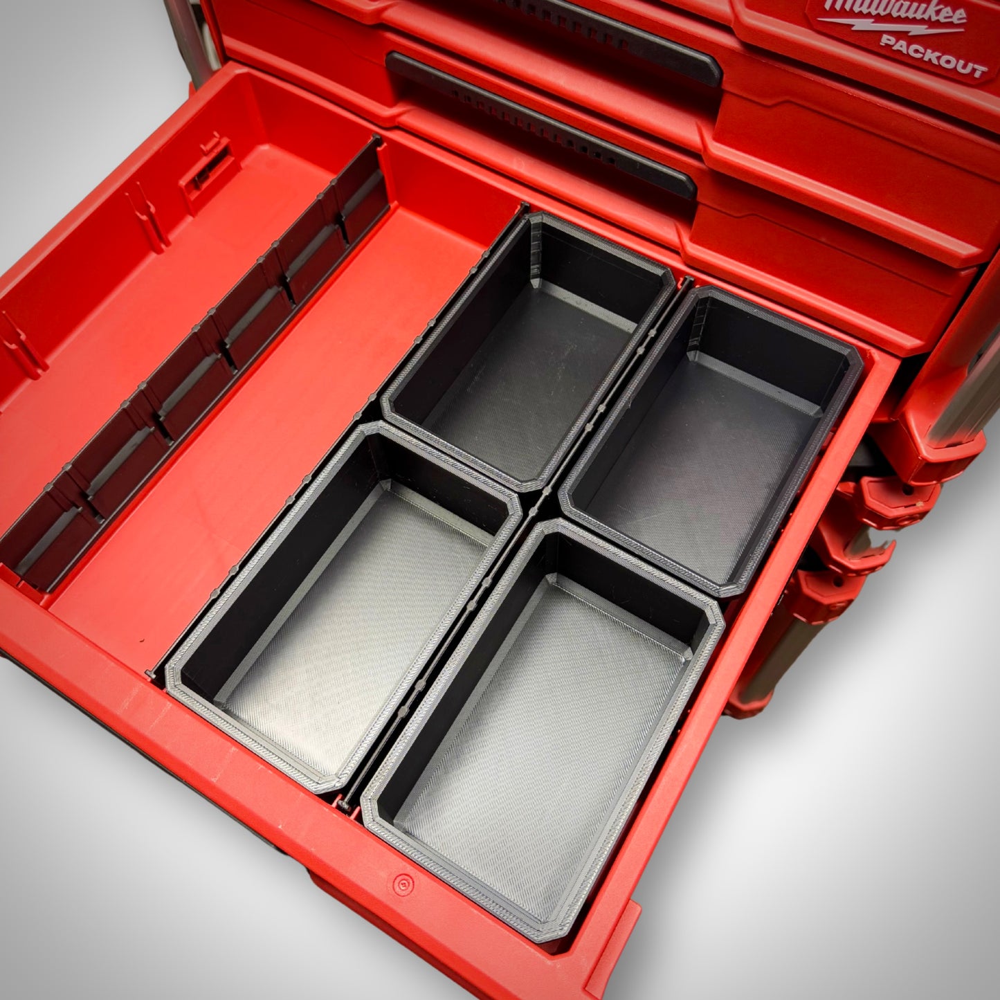 Four empty Milwaukee PACKOUT™ Full Bins arranged side by side inside the 4-Drawer Toolbox, ready for large item storage.