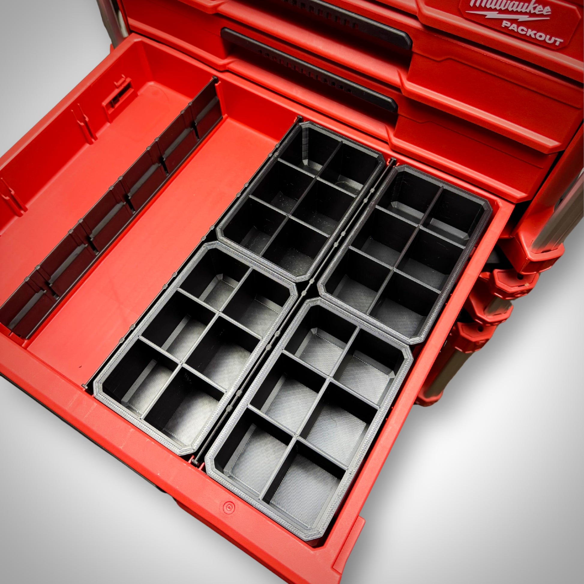 Four empty Milwaukee PACKOUT™ 6-Way Divider Bins lined up side by side inside the 4-Drawer Toolbox for maximum small part storage.