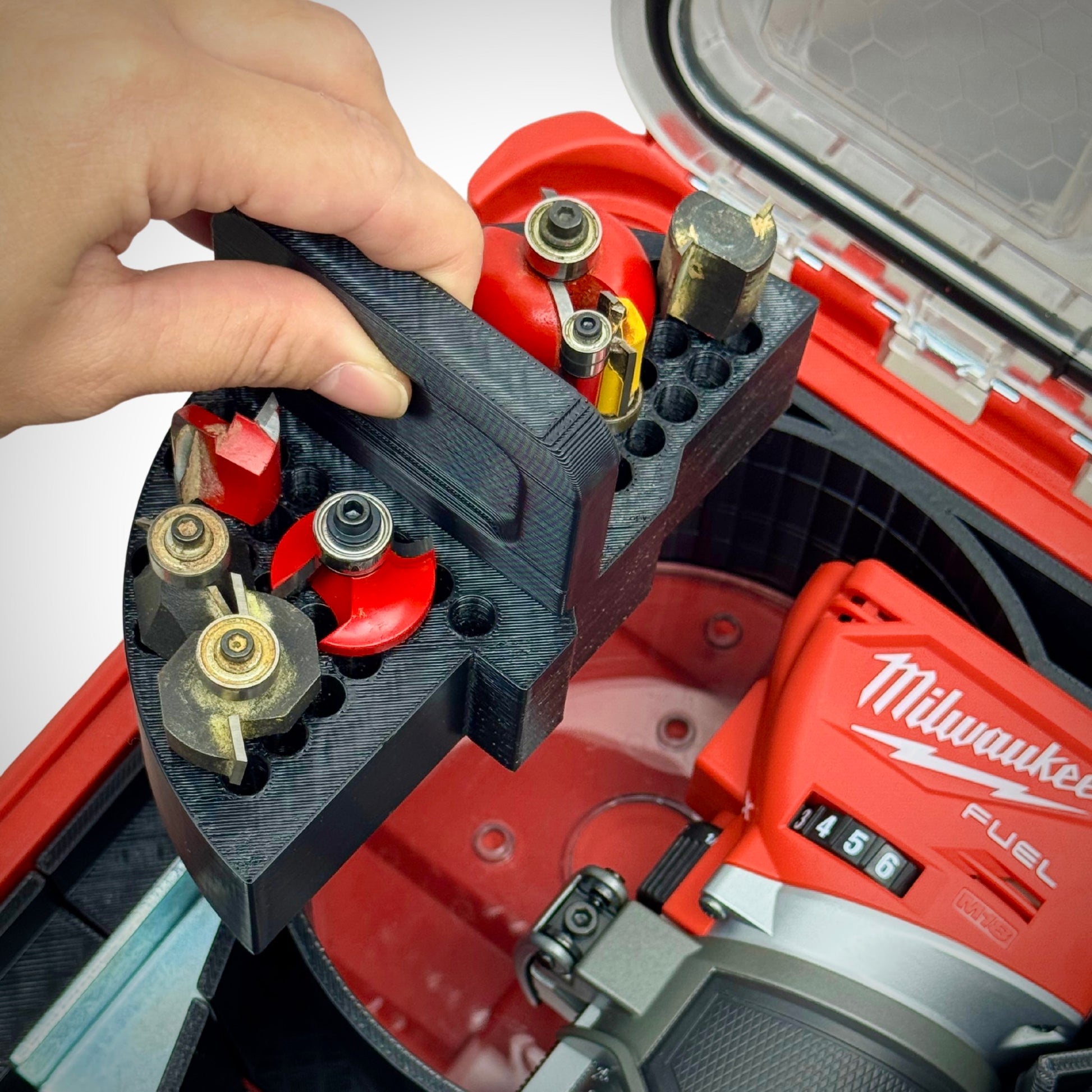 Hand removing an accessory tray from the router insert, revealing hidden storage beneath the removable section.
