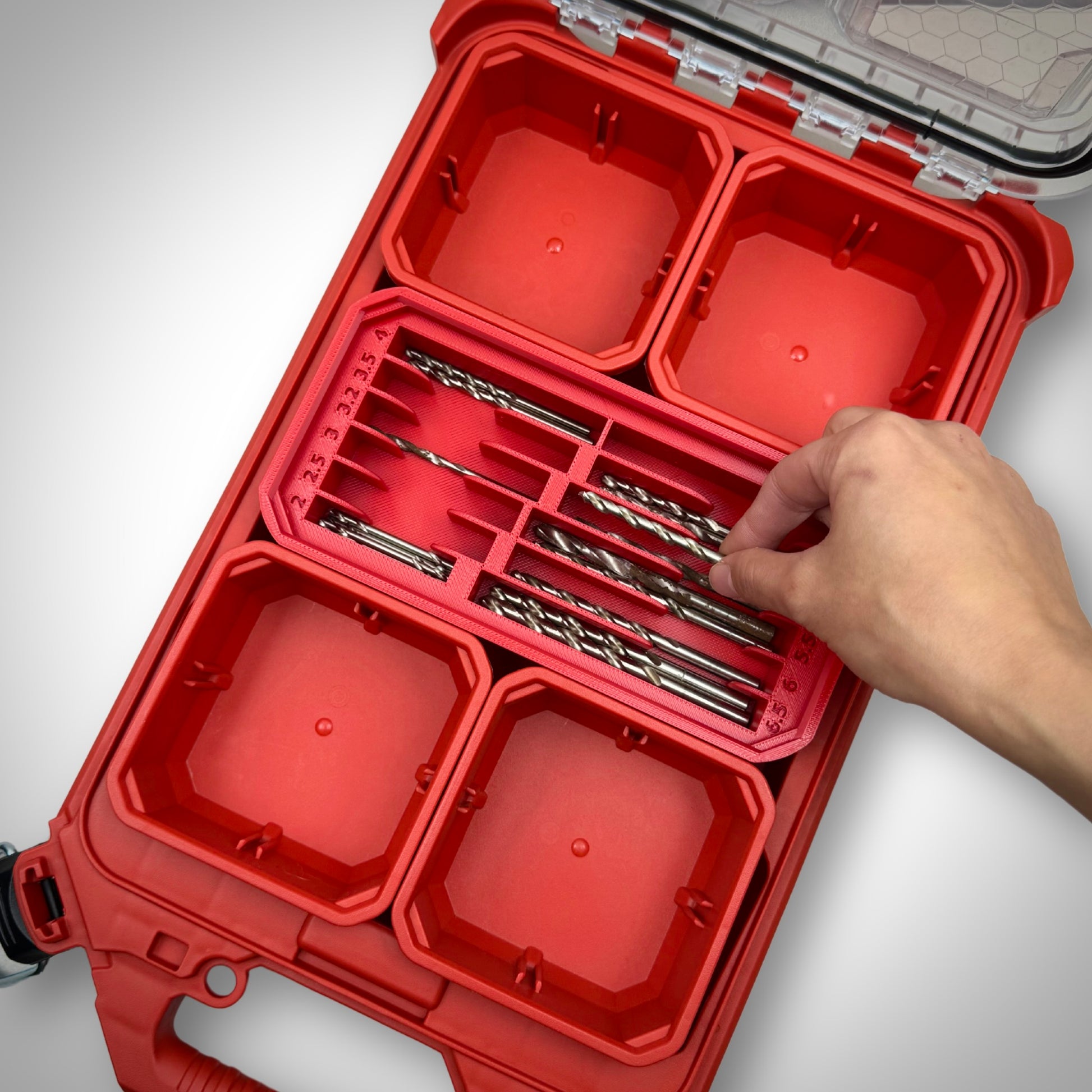 Hand picking a metric drill bit from the fully loaded red Metric Drill Bit Holder Insert inside the Milwaukee PACKOUT™ Low Profile Organiser, showing easy tool access.