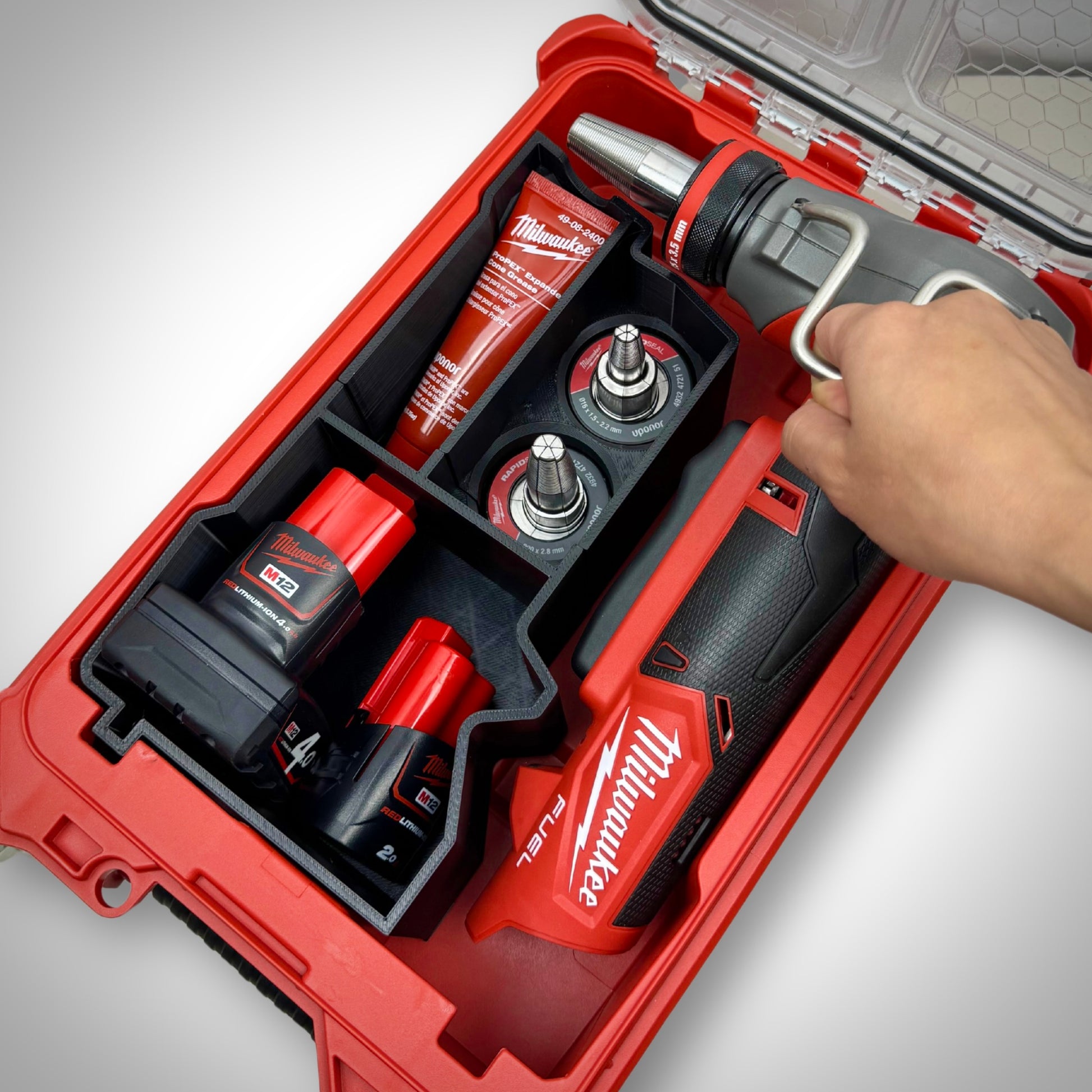 Hand lifting the M12 Expansion Tool out of the insert, showing intuitive layout and convenient access to attachments.