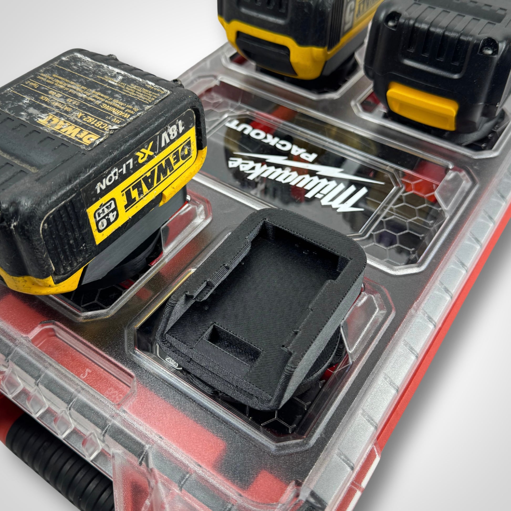 Adaptor insert placed on the PACKOUT™ Compact Organiser, compartments visible and empty, designed specifically for DeWalt 18V batteries.