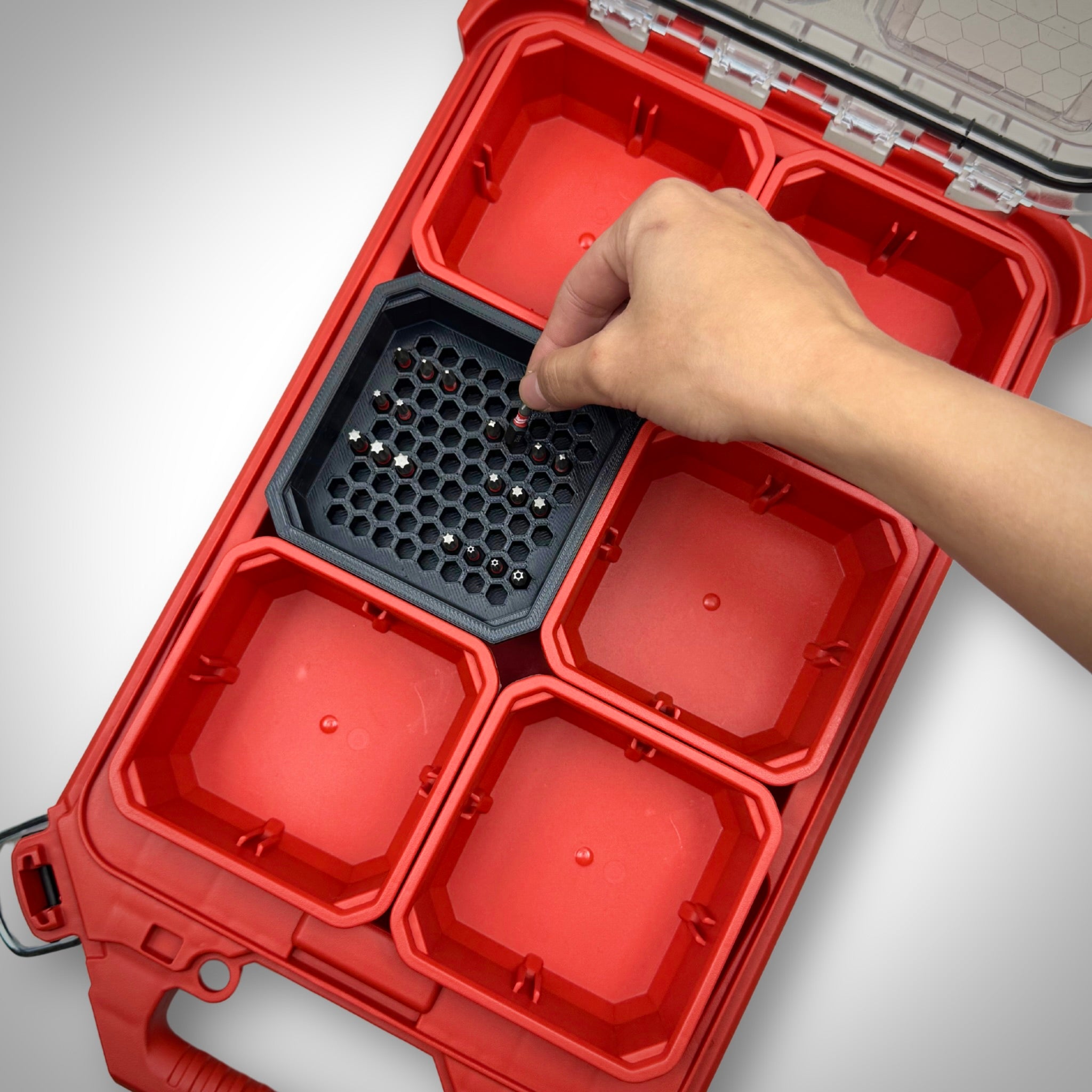 Hand lifting a hex bit from the black Hex Bit Holder insert inside a Milwaukee PACKOUT™ bin, showing quick and organised bit access.