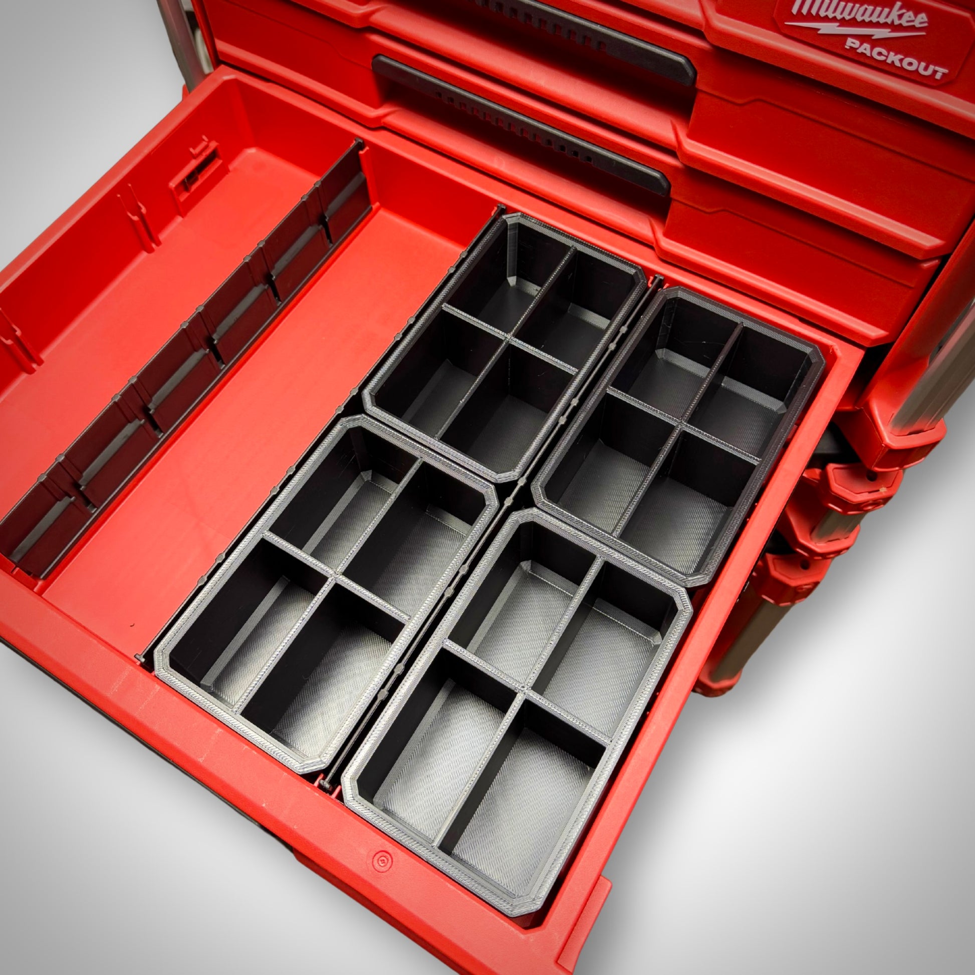 Four empty Milwaukee PACKOUT™ 6-Way Divider Bins lined up side by side inside the 4-Drawer Toolbox for maximum small part storage.