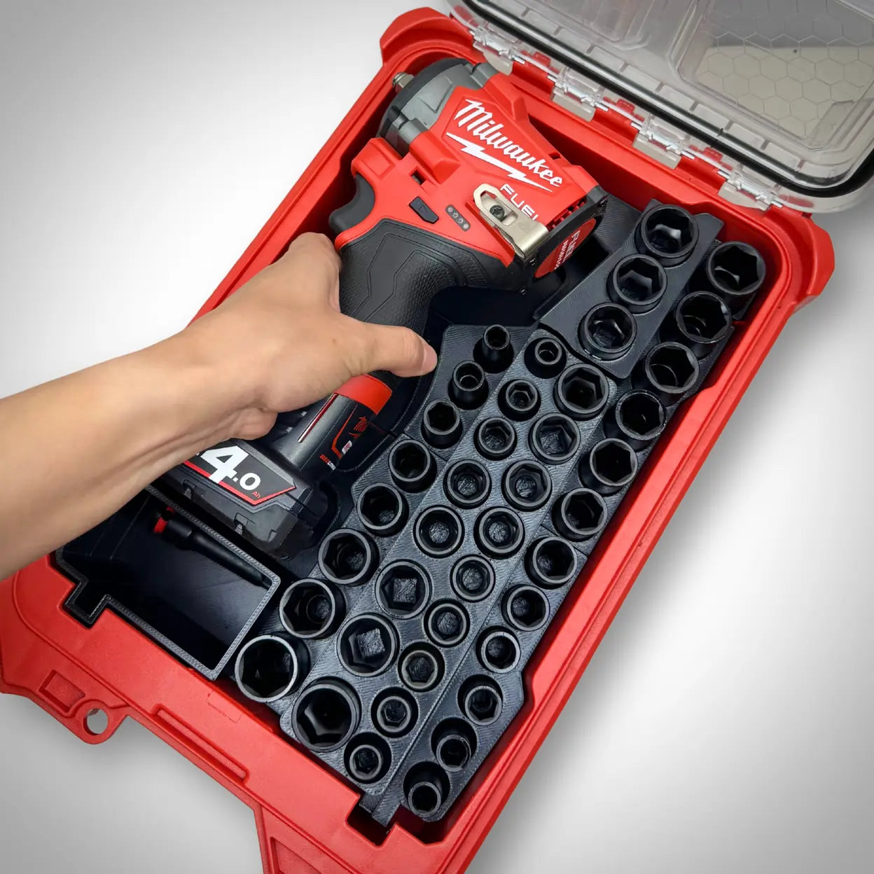 Hand reaching into the insert to grab the M12 Stubby Impact Wrench, showing easy access and organised layout of sockets and tool inside the PACKOUT™ Compact Organiser.